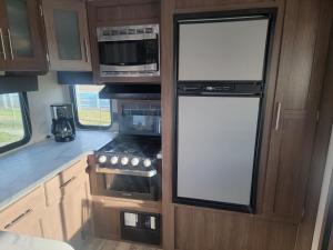 a kitchen in an rv with two large windows at Cozy Camper in Newfield