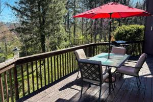 a table and chairs on a deck with an umbrella at Circular Mountain Retreat in Brevard