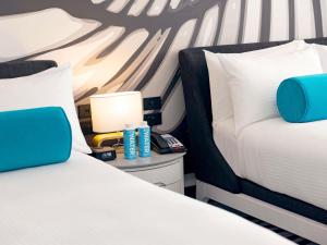 two beds with white and blue pillows and a lamp at Pullman Cairns International in Cairns