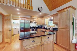 a kitchen with wooden cabinets and a clock on the wall at Talking River Chalet in Murphy