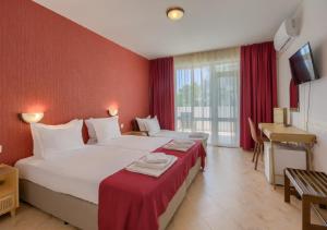a bedroom with two beds with red walls and a desk at Hotel Feniks Lozenets in Lozenets