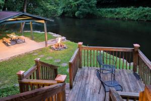 eine Terrasse mit Stühlen und einer Feuerstelle neben dem Wasser in der Unterkunft River Romance in Sylva + 16 Fotos