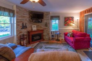a living room with a red couch and a fireplace at The Reed House in Dillsboro