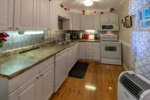 a kitchen with white cabinets and a wooden floor at The Reed House in Dillsboro