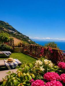 a table with a hat sitting on a balcony with flowers at Villa Degli Ulivi in Furore
