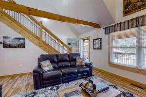 a living room with a leather couch and a staircase at The Mountain Haven in Maggie Valley