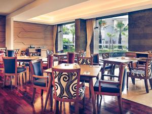 a restaurant with wooden tables and chairs and a large window at Grand Mercure Bandung Setiabudi in Bandung