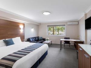 a hotel room with a large bed and a kitchen at Mercure Wagga Wagga in Wagga Wagga +51 photos