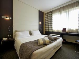 a hotel room with a large bed and a window at Mercure Bergamo Aeroporto in Stezzano +60 photos