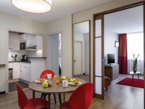 a living room with a table and red chairs at Aparthotel Adagio Genève Mont-Blanc in Geneva +93 photos