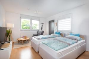 a white bedroom with two beds and a table at Modernes Apartment mit Küche, Parkplatz, WLAN - Nähe Schwäbisch Gmünd in Waldstetten
