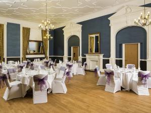 a banquet hall with white tables and chairs and a chandelier at Mercure Darlington King's Hotel in Darlington