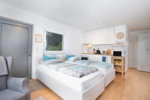 a white bedroom with a bed and a chair at Modernes Apartment mit Küche, Parkplatz, WLAN - Nähe Schwäbisch Gmünd in Waldstetten