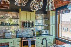 a kitchen with green cabinets and a brick wall at Brick Loft Penthouse on Main in Brevard +15 photos