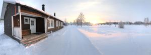 a cabin in a snow covered field with the sun setting at Nilimella Camping & Resort in Sodankylä +2 photos