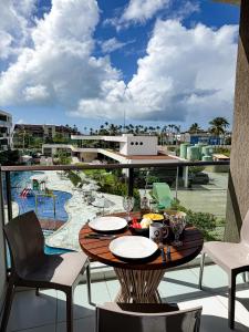a table on a balcony with a view of a pool at Makia Beach Experience- Flat 202D in Ipojuca