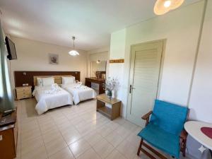 a bedroom with two beds and a blue chair at Ta Kalamakia Apartments in Vatera
