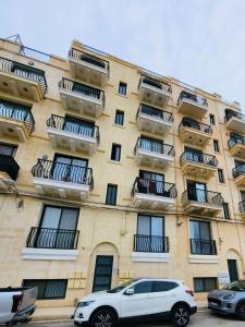 a white car parked in front of a building at Del Mar Apartment in Żebbuġ