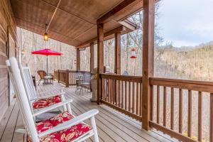 a porch with two chairs and a table on it at Tree Top Cabin in Sylva
