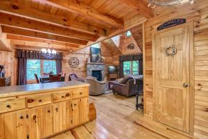 a log cabin kitchen and living room with a fireplace at Forest Hideaway in Maggie Valley