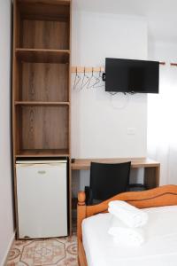 a bedroom with a bed and a desk and a tv at Hotel Alga Velipoje in Velipojë