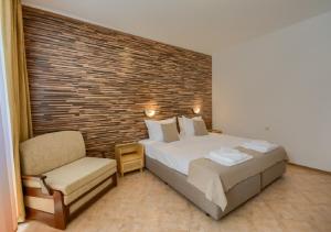 a bedroom with a large bed and a chair at Hotel Feniks Lozenets in Lozenets