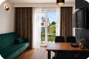 a living room with a green couch and a table at Apartamenty Zator Jaśminowa in Zator