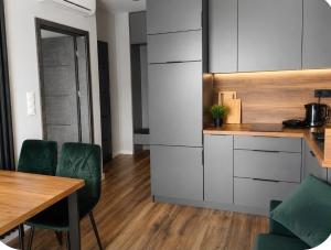 a kitchen with a table and some green chairs at Apartamenty Zator Jaśminowa in Zator