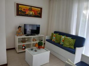 a living room with a blue couch and a tv at Apto 2/4 resort TreeBies- Subaúma in Subaúma