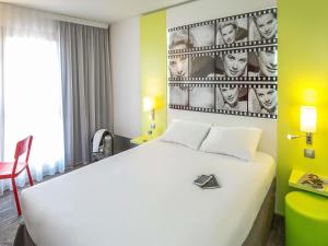 a bedroom with a white bed and a wall with photographs at ibis Styles Cannes Le Cannet in Cannes