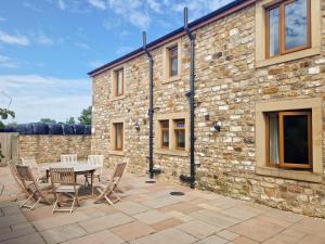 a patio with a table and chairs in front of a stone building at 4 Bed in Forton oc-81290 in Forton