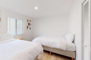 a white bedroom with two beds and a window at The Crocket Fortune in Murphy
