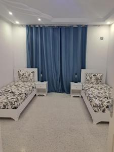 two beds in a room with blue curtains at villa mellita in Mellita +27 photos