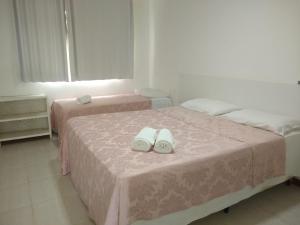 two beds with pink sheets and white shoes on them at Apto 2/4 resort TreeBies- Subaúma in Subaúma +13 photos