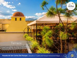 a yellow building with a tower and palm trees at Posada de San Carlos del Parque in Antigua Guatemala