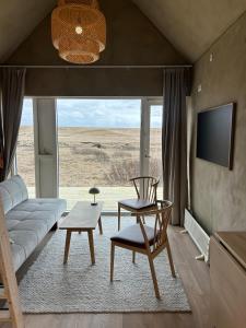 a living room with a couch and a table and a tv at Cozy cottage with a view in Hella