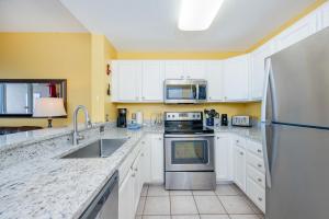 a kitchen with white cabinets and a stainless steel refrigerator at The Dunes 503 in Gulf Shores