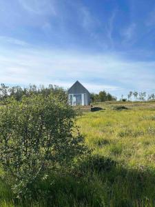 a small house in the middle of a field at Cozy cottage with a view in Hella