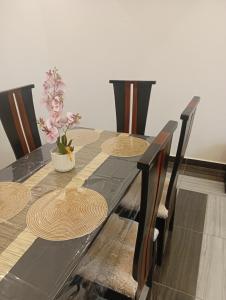 a dining table with four chairs and a plant on it at Résidence Prestige KGV Appt 302 in Douala