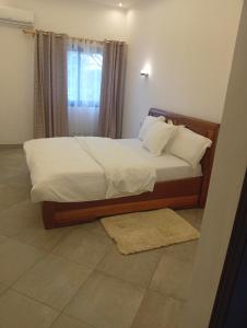 a bedroom with a bed with white sheets and a window at Résidence Prestige KGV Appt 302 in Douala
