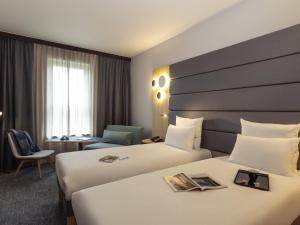 a hotel room with two beds and a desk at Novotel Brussels Centre Midi in Brussels