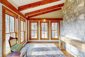 a living room with a stone wall and windows at Moss Creek Cabin in Sylva +18 photos