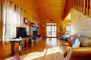 a living room with a couch and a tv in a cabin at The Rushing Creek Cabin in Topton