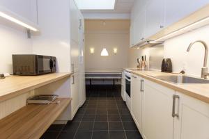 een keuken met witte kasten, een wastafel en een magnetron bij Give Apartment in Billund
