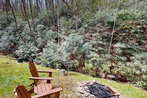 two wooden chairs sitting next to a fire pit at Creeksong Cabin in Topton