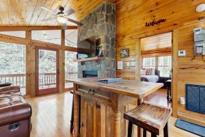 a log cabin kitchen with a large stone fireplace at Creeksong Cabin in Topton