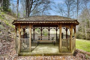 a wooden gazebo with a bench in a park at Creeksong Cabin in Topton +10 photos