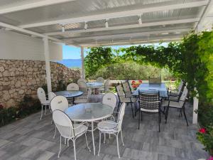 a patio with tables and chairs and a stone wall at Apartments Villa Katarina in Tučepi +44 photos