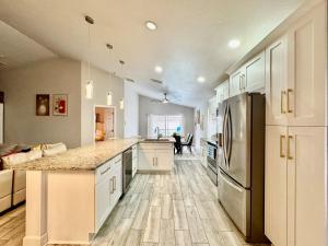 a kitchen with white cabinets and a stainless steel refrigerator at Modern 4BR2BA with pool in gated community in Kissimmee