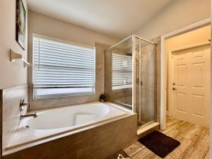 a bathroom with a tub and a shower and a window at Modern 4BR2BA with pool in gated community in Kissimmee +37 photos